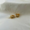 Gold crescent-shaped stud earrings covered with crystal stones on white fabric background.