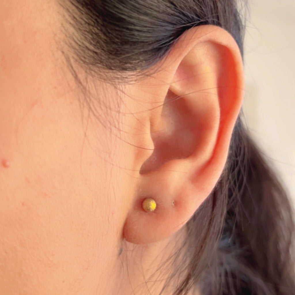 small textured gold stud earrings on soft neutral background