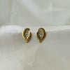 Textured gold leaf-shaped stud earrings with crystal accents displayed on white fabric.