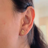 gold stud earrings in leaf shape on neutral background