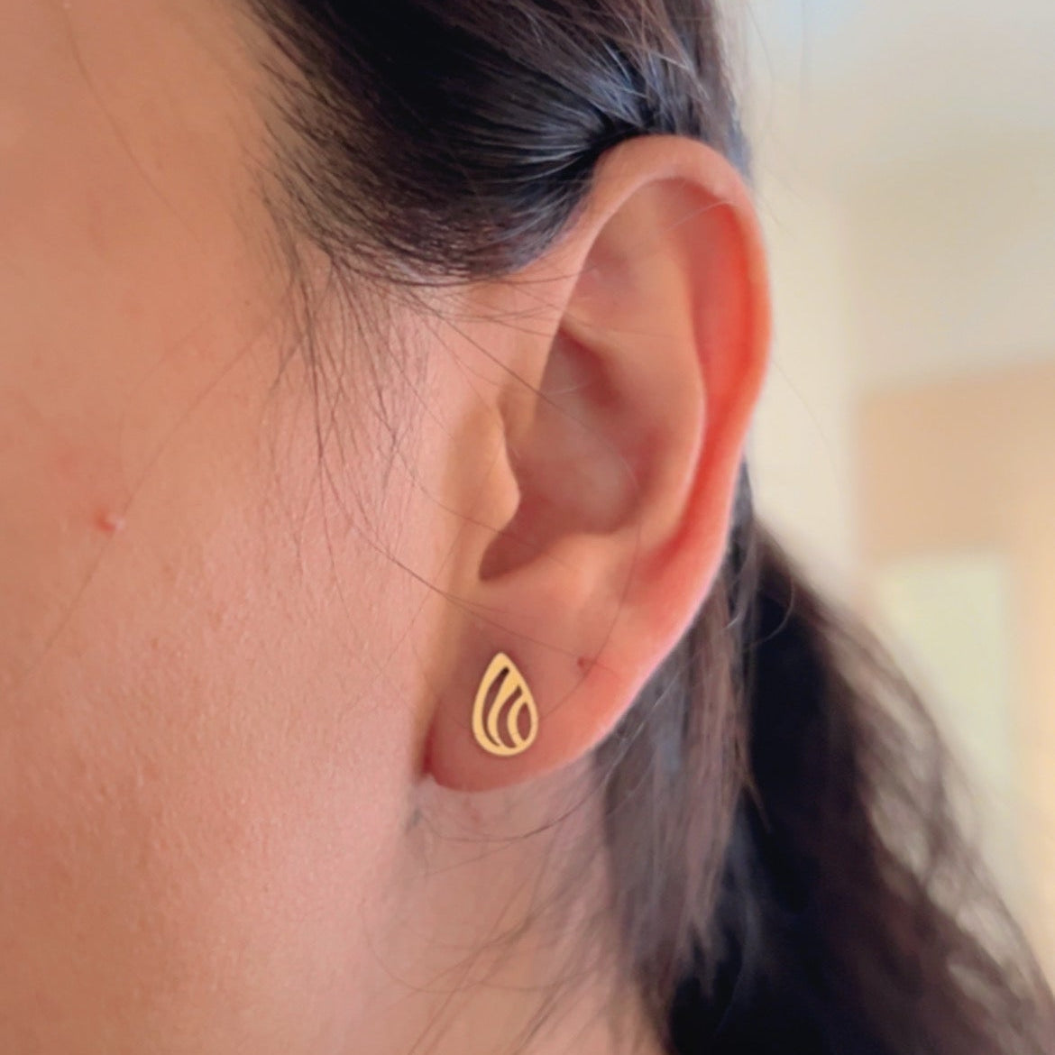 gold stud earrings in leaf shape on neutral background