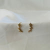 Gold floral vine-style ear climber earrings with crystal accents placed on white fabric.