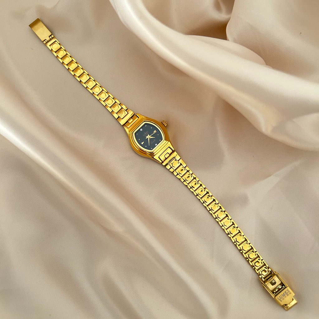 Gold Circle dial wristwatch with linked bracelet placed on soft beige satin background, elegant minimal design.