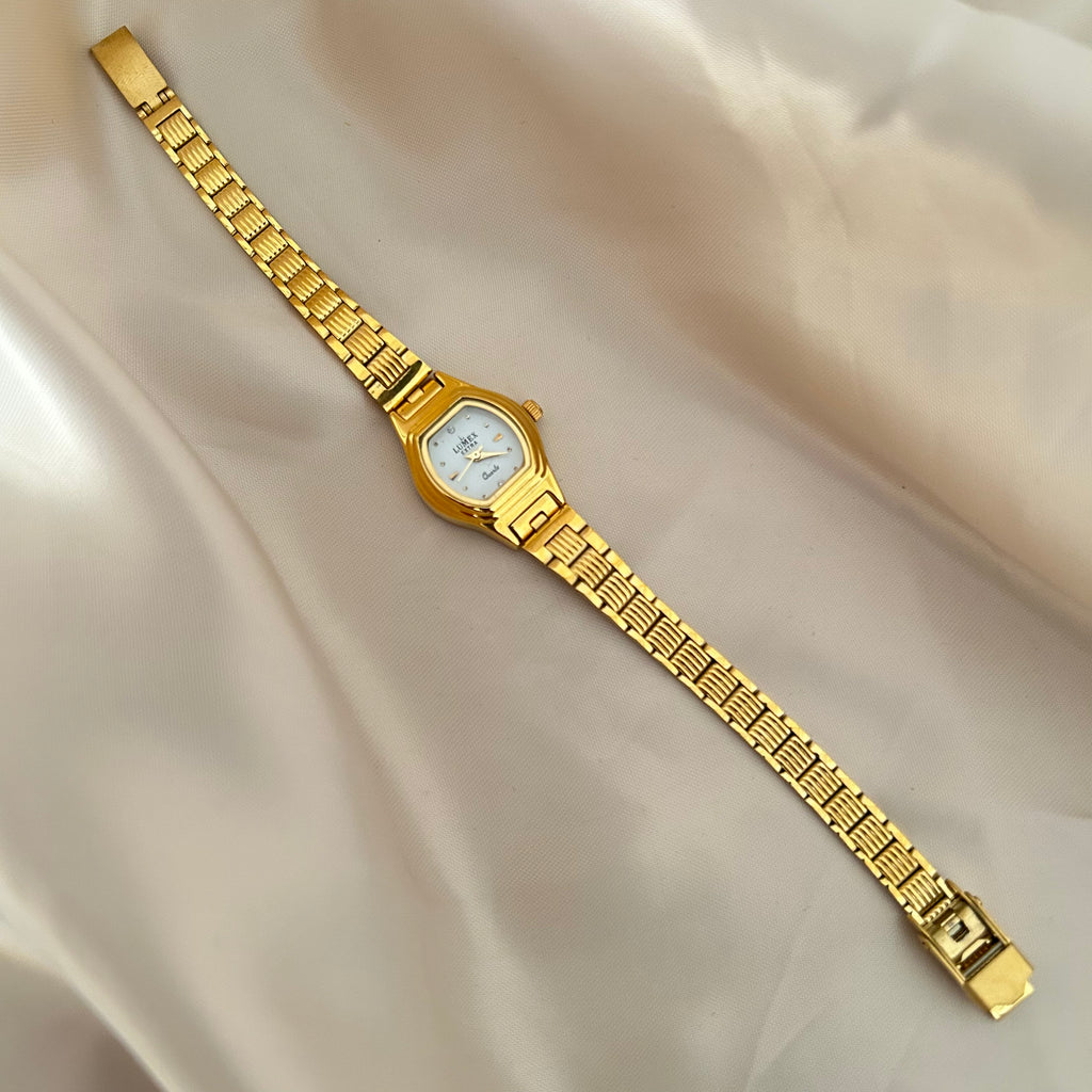 Gold Circle dial wristwatch with linked bracelet placed on soft beige satin background, elegant minimal design.