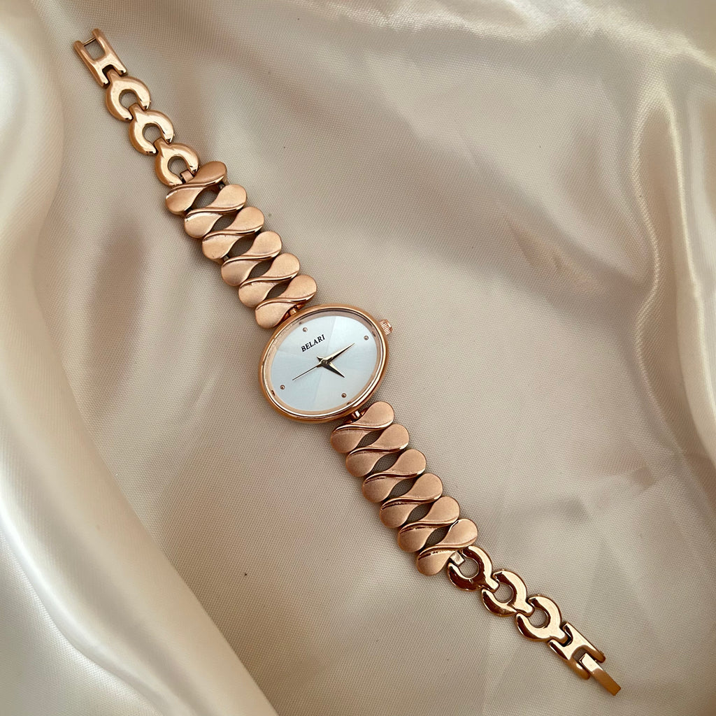 gold wristwatch with chain style bracelet and round dial placed on satin cloth.