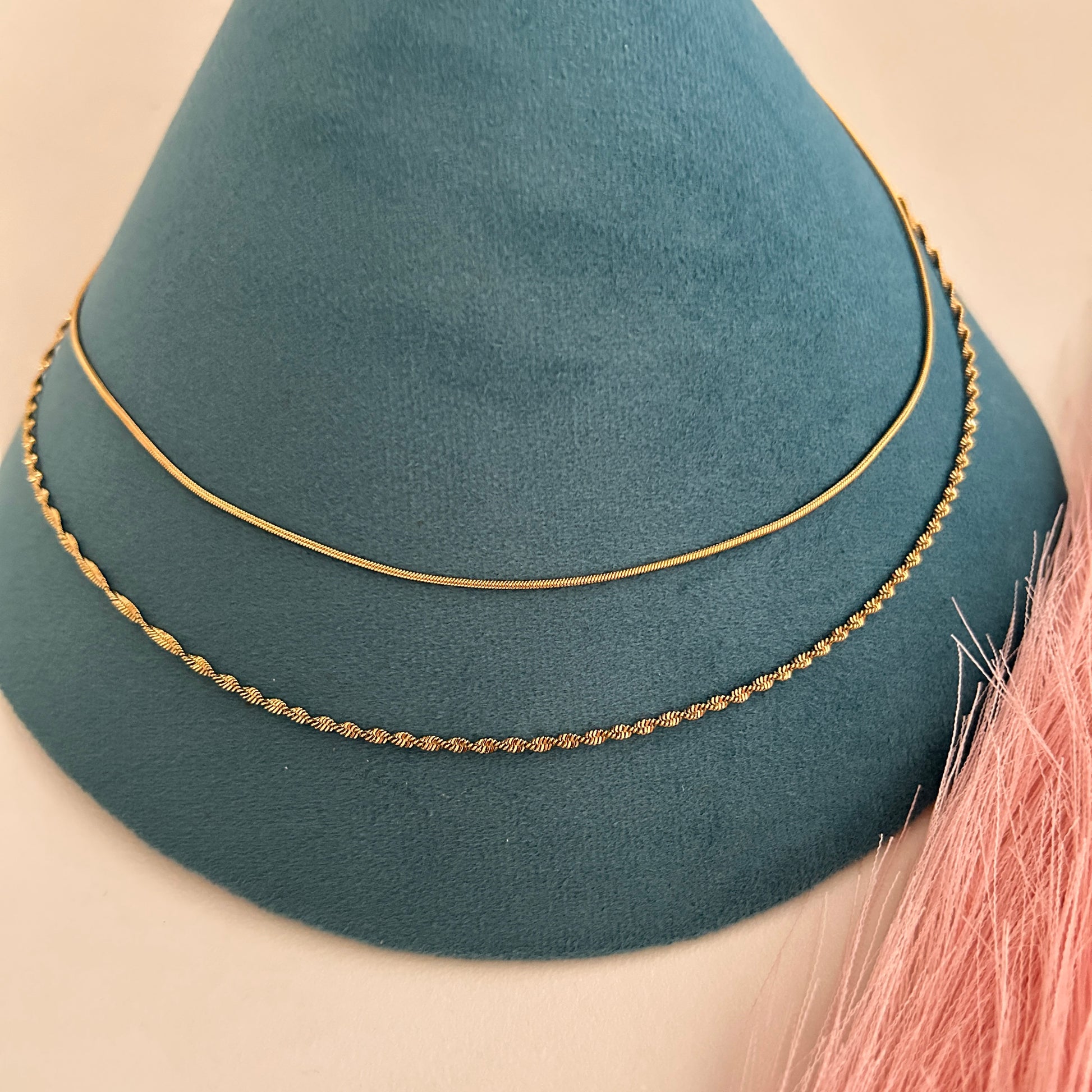 Minimal twin-chain gold waist band with smooth and twisted chain layers on display stand.