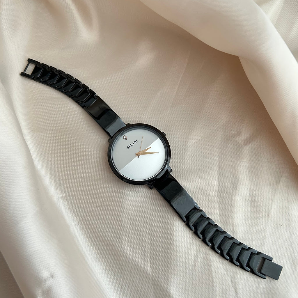 Black dial wristwatch with dark strap placed on satin cloth background.