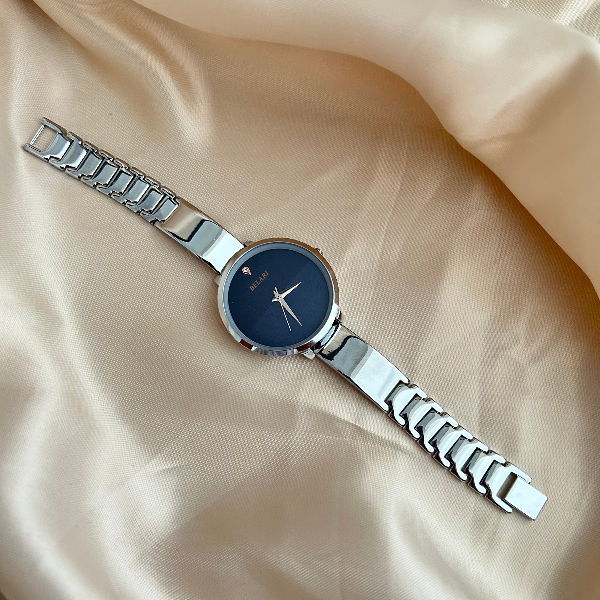 Silver Body wristwatch with silver strap on soft fabric background.