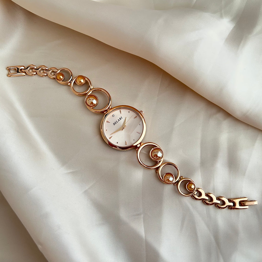Rose gold wristwatch with pearl bracelet design and round dial on soft satin background.
