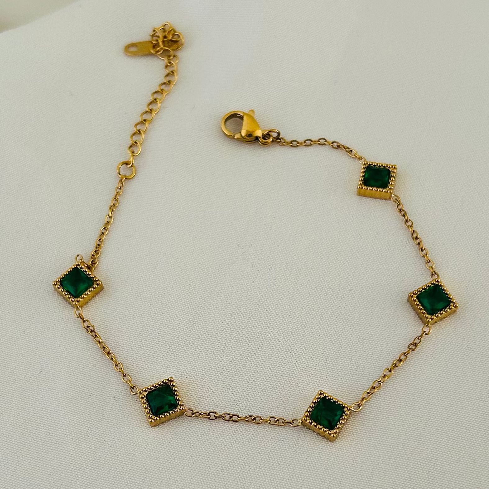 Gold bracelet with green square stones